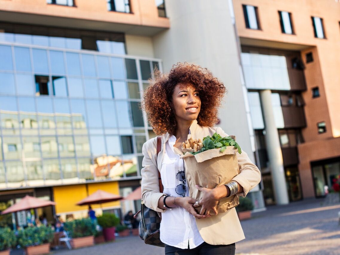 Woman walking and holding shopping bag.